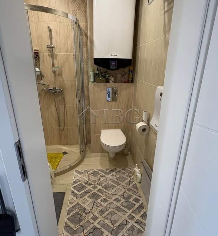 Small bathroom with shower, toilet, and water heater in Pomorie residence.