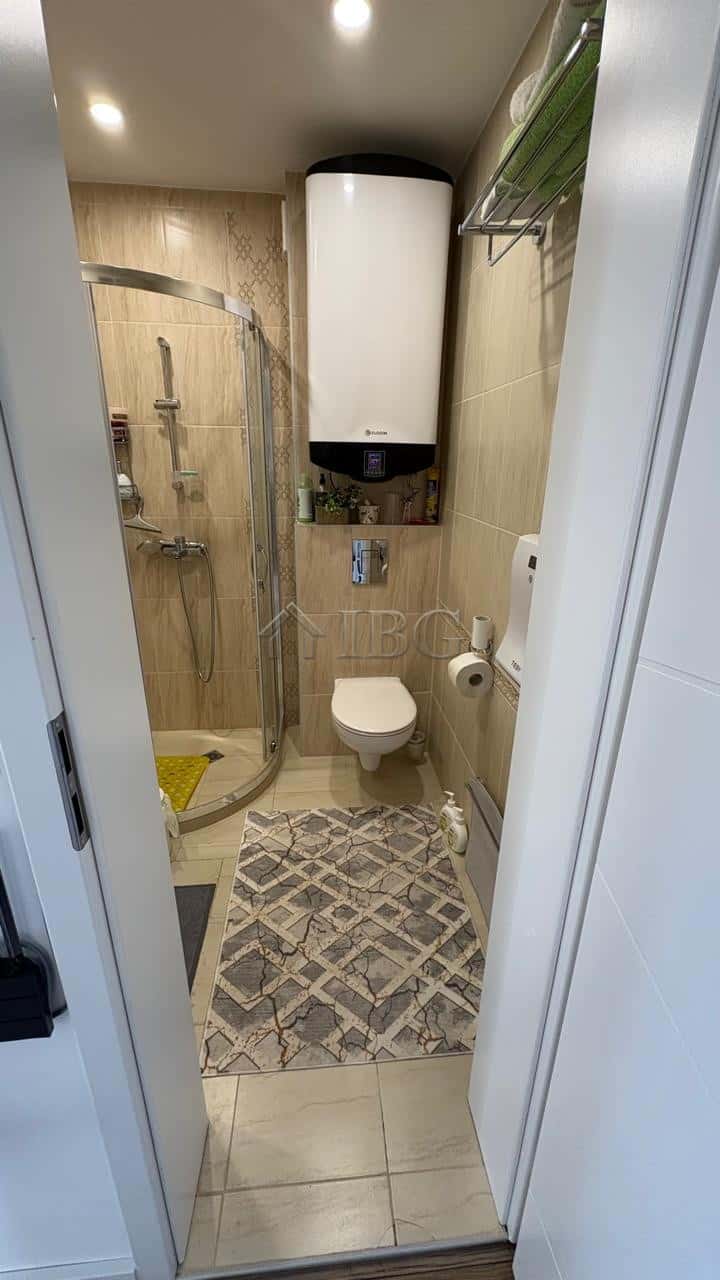 Small bathroom with shower, toilet, and water heater in Pomorie residence.