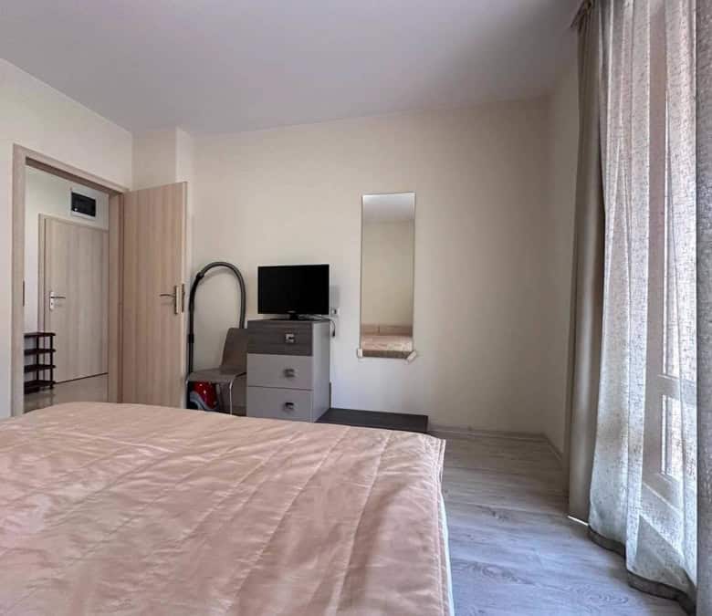Interior view of a 1-bedroom apartment in Sveti Vlas, near the sea, with a bed, TV, and balcony.