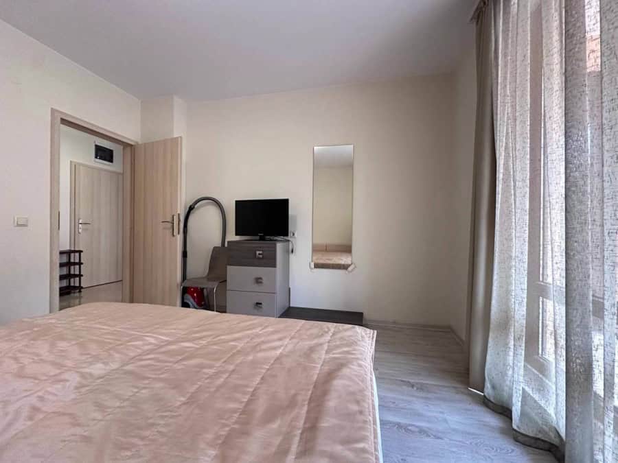 Interior view of a 1-bedroom apartment in Sveti Vlas, near the sea, with a bed, TV, and balcony.