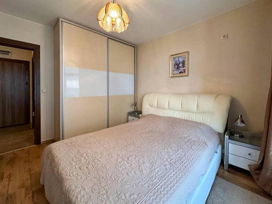 Spacious bedroom with a large wardrobe, comfortable bed, and warm lighting in a sunny apartment.