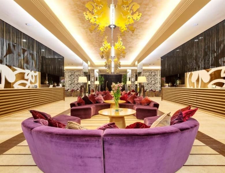 Elegant hotel lobby featuring plush purple seating, ornate lighting, and stylish interior design.