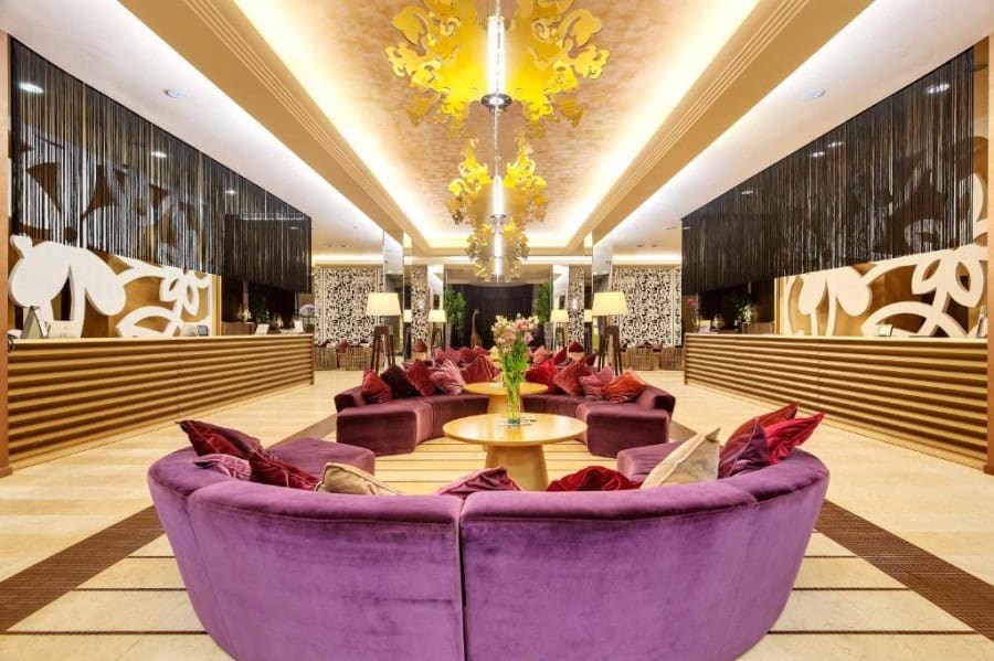 Elegant hotel lobby featuring plush purple seating, ornate lighting, and stylish interior design.