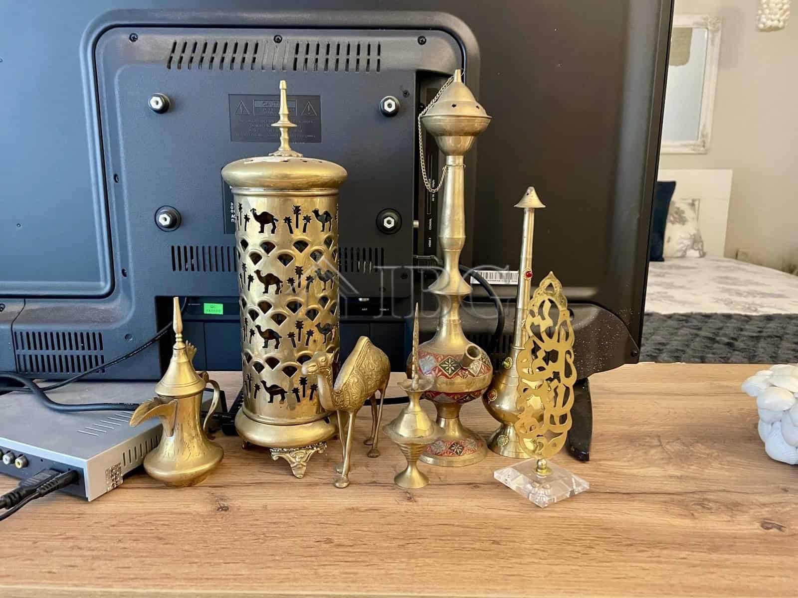 Brass decorative ornaments displayed on a wooden desk in a contemporary apartment setting.