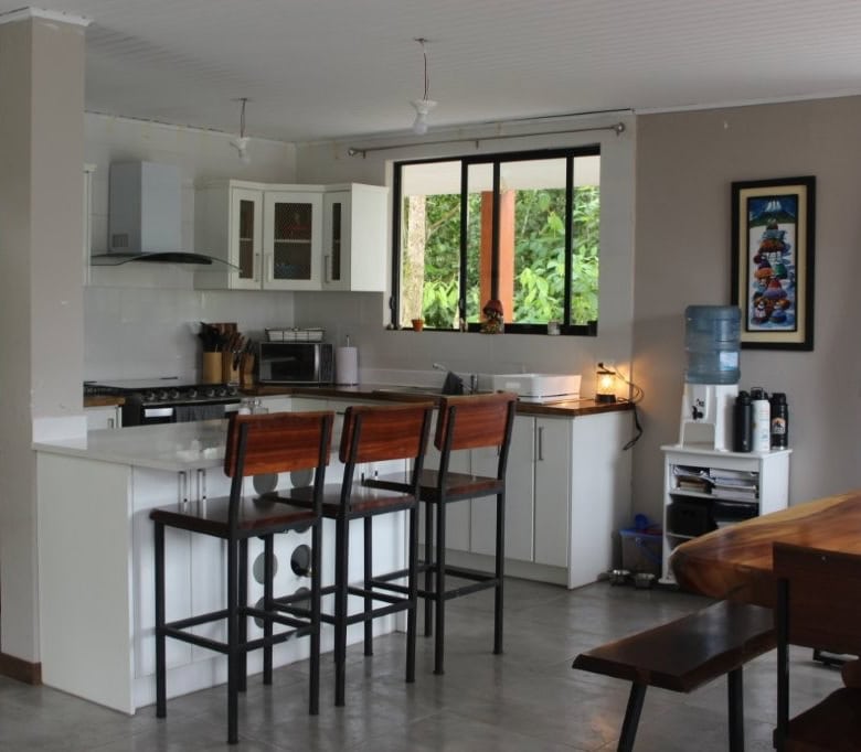 Bright kitchen with white cabinets, stainless steel appliances, and large window.