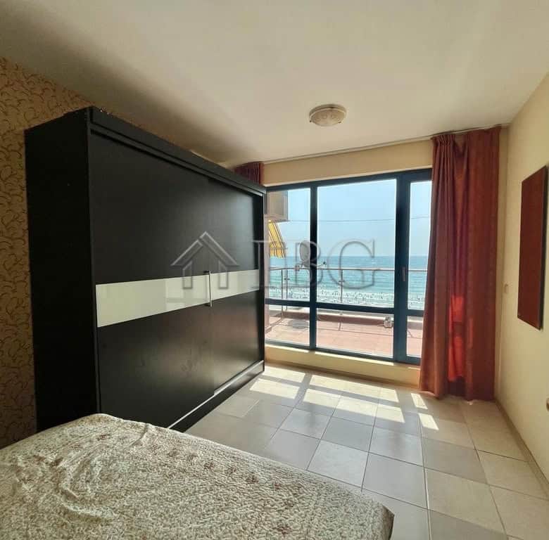 Bright bedroom with ocean view, balcony, and summer sunlight.