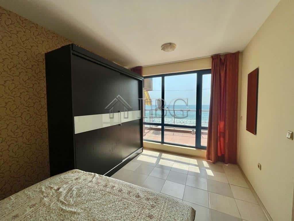 Bright bedroom with ocean view, balcony, and summer sunlight.