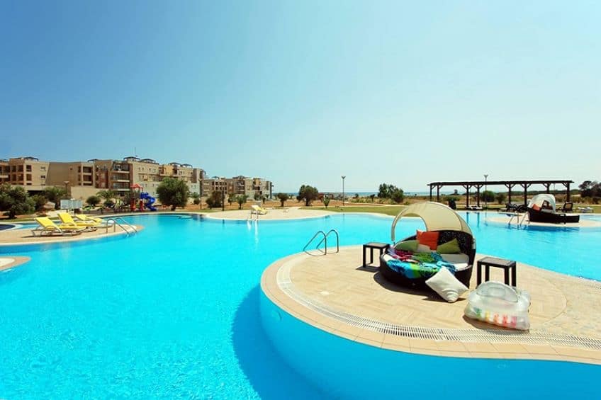 Poolside view of the luxurious Thalassa Beach Resort with clear blue waters and sun loungers.