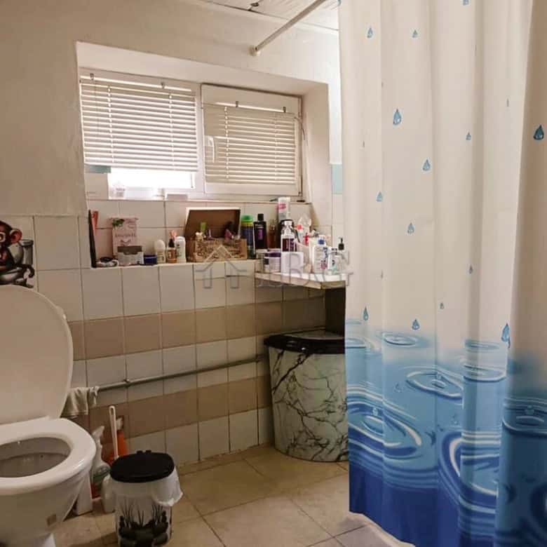 Interior of a bathroom with a window, shower curtain, and various toiletries.