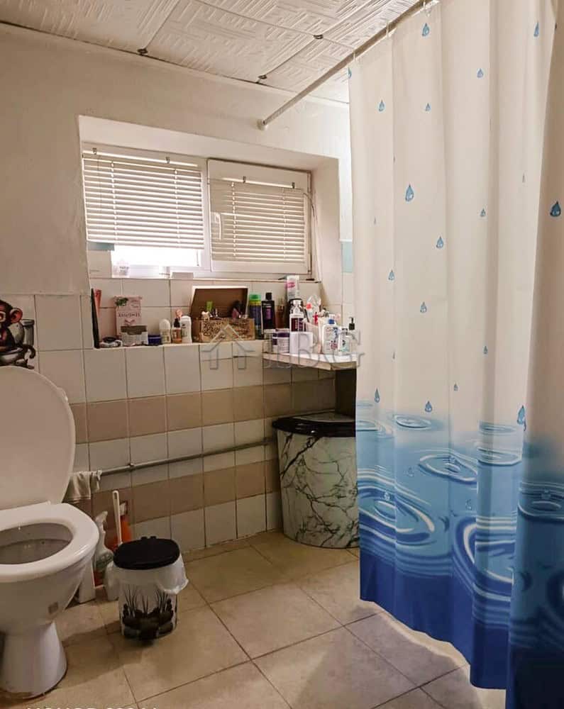 Interior of a bathroom with a window, shower curtain, and various toiletries.