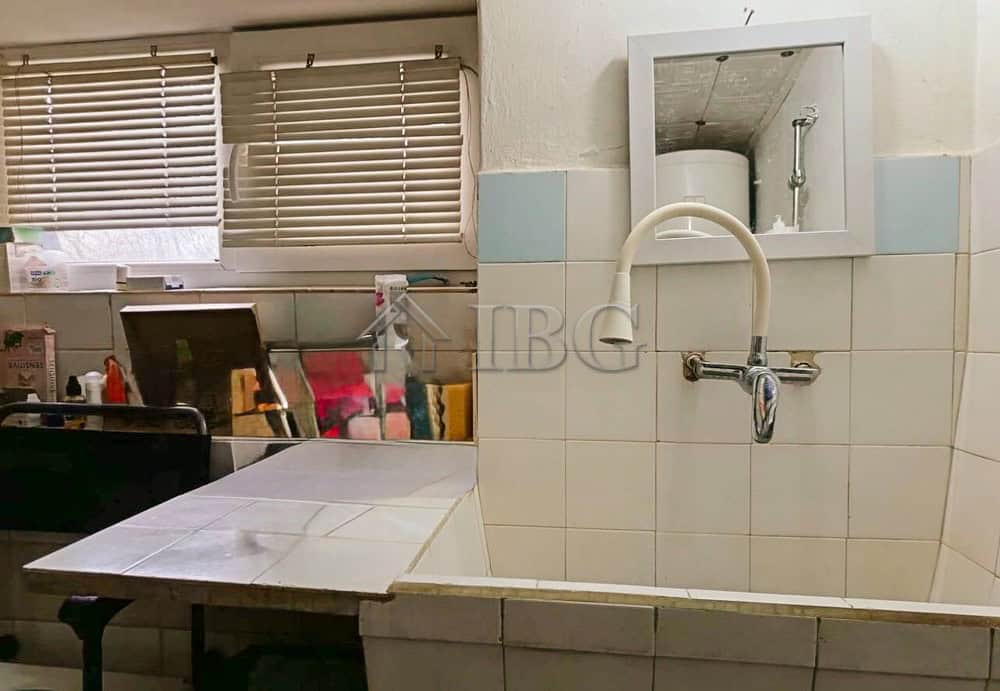 Interior laundry area with sink, window, and storage space in a well-maintained home.