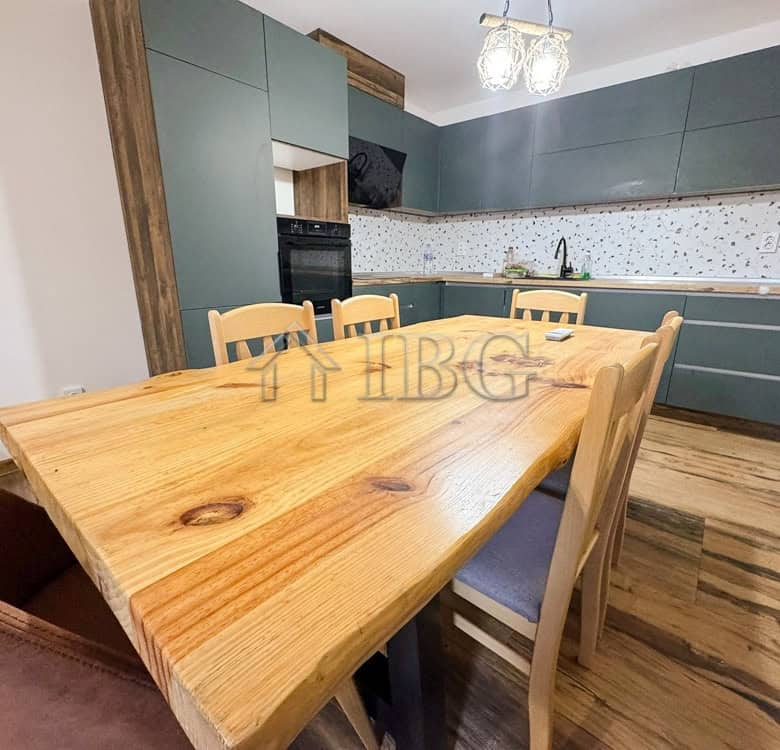 Spacious kitchen in a luxury family apartment, featuring a wooden dining table and contemporary gree.