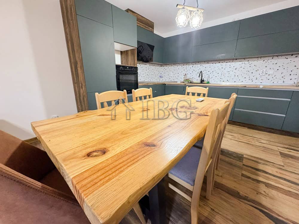 Spacious kitchen in a luxury family apartment, featuring a wooden dining table and contemporary gree.