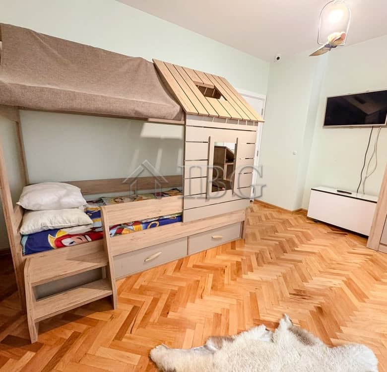 Bright children's room featuring a house-shaped bed with storage drawers and a playful design.