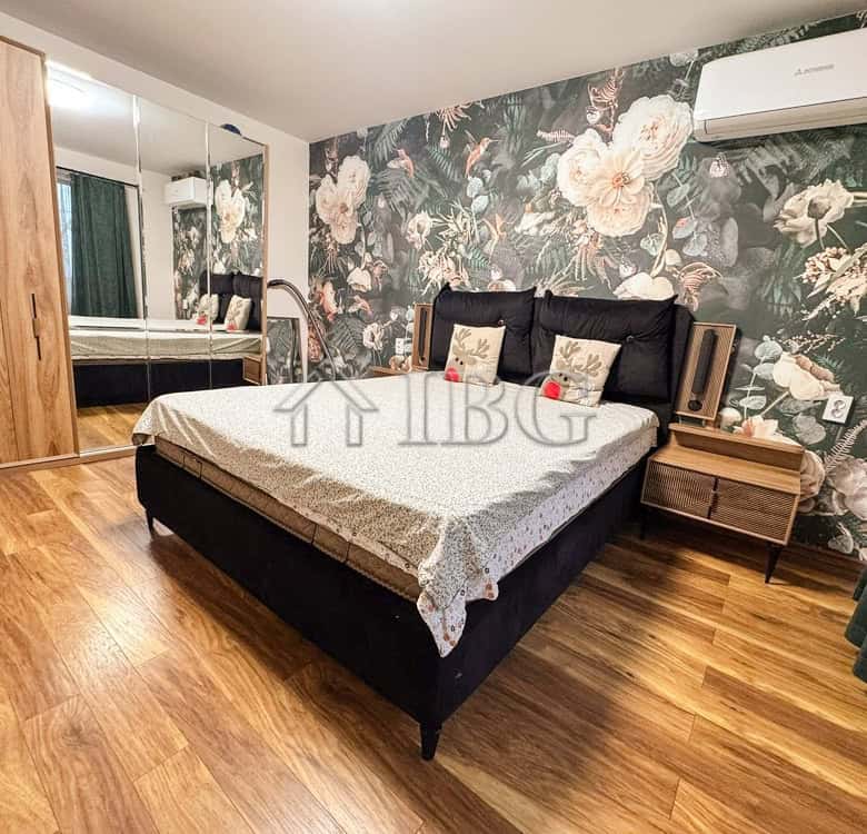 Modern bedroom with floral accent wall and wooden flooring.