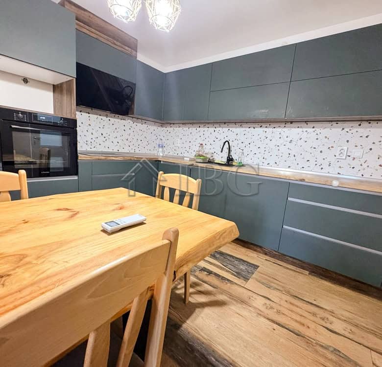 Spacious modern kitchen with blue cabinets and wooden dining table in Ruse apartment.