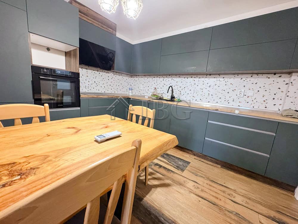 Spacious modern kitchen with blue cabinets and wooden dining table in Ruse apartment.