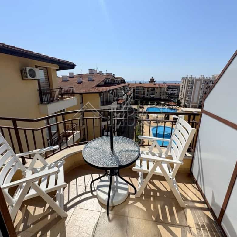 Bright balcony with outdoor seating overlooking the town and pool area.