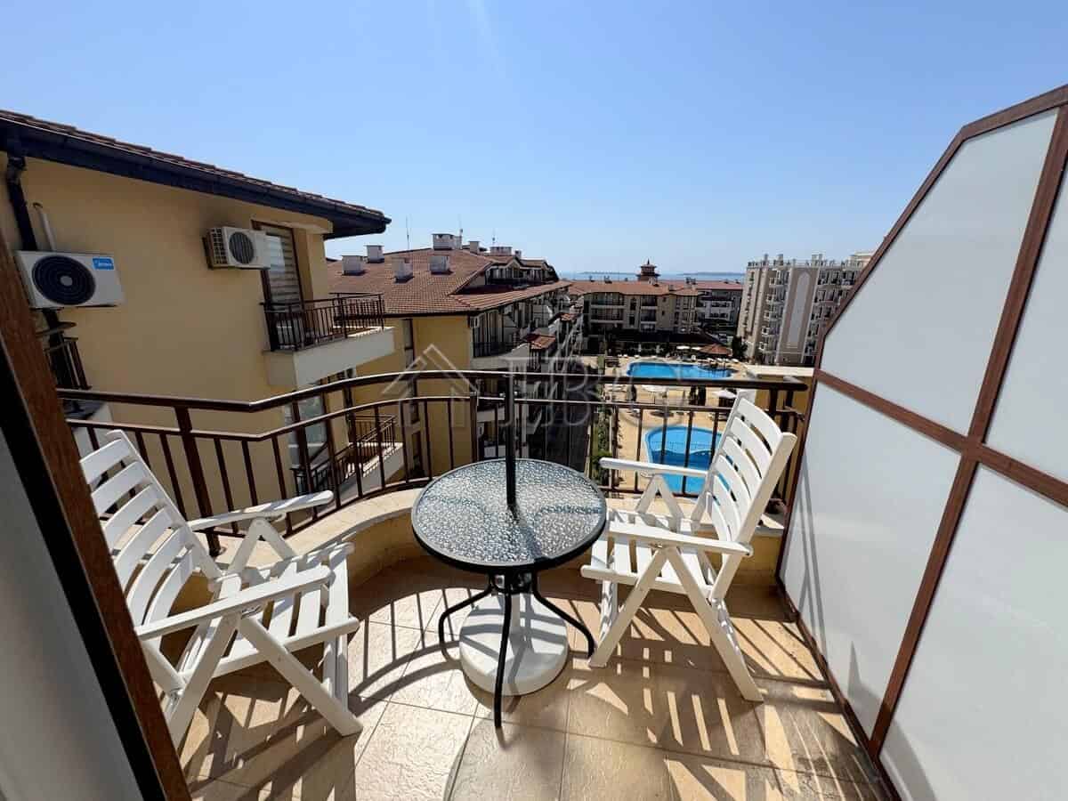 Bright balcony with outdoor seating overlooking the town and pool area.