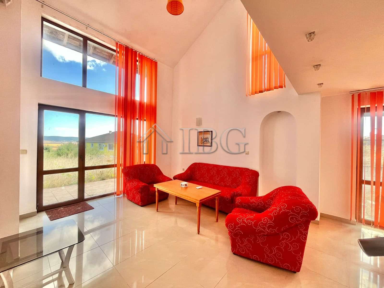 Cozy living room with large windows and vibrant orange curtains in Aleksandrovo, Burgas.