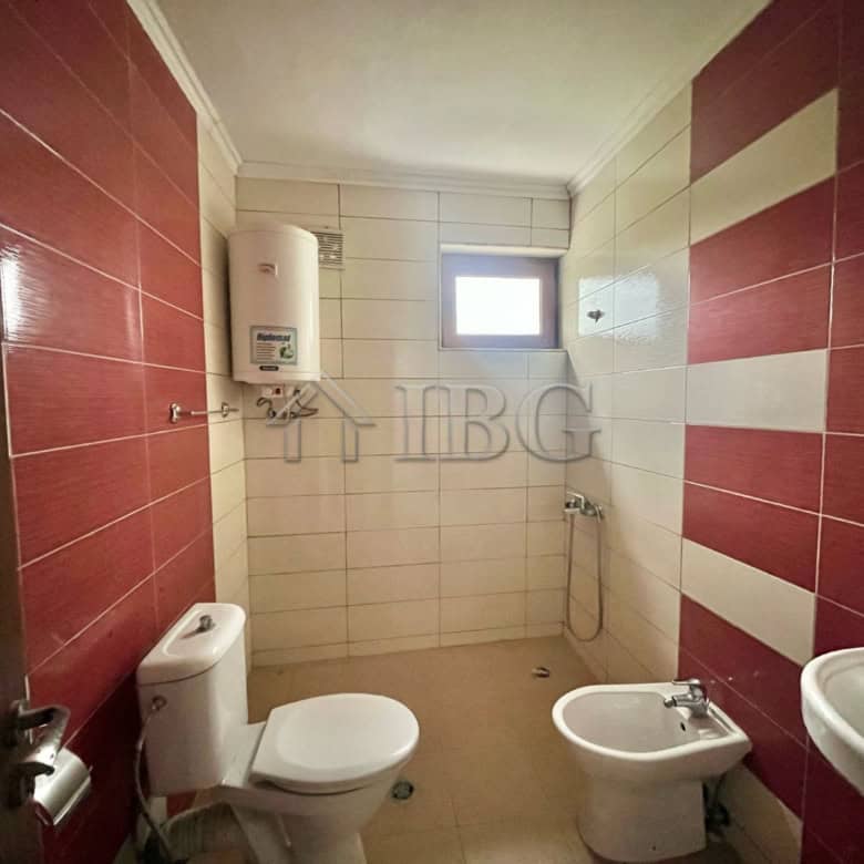 Cozy bathroom with modern fixtures, white and red tiled walls, and a small window for natural light.