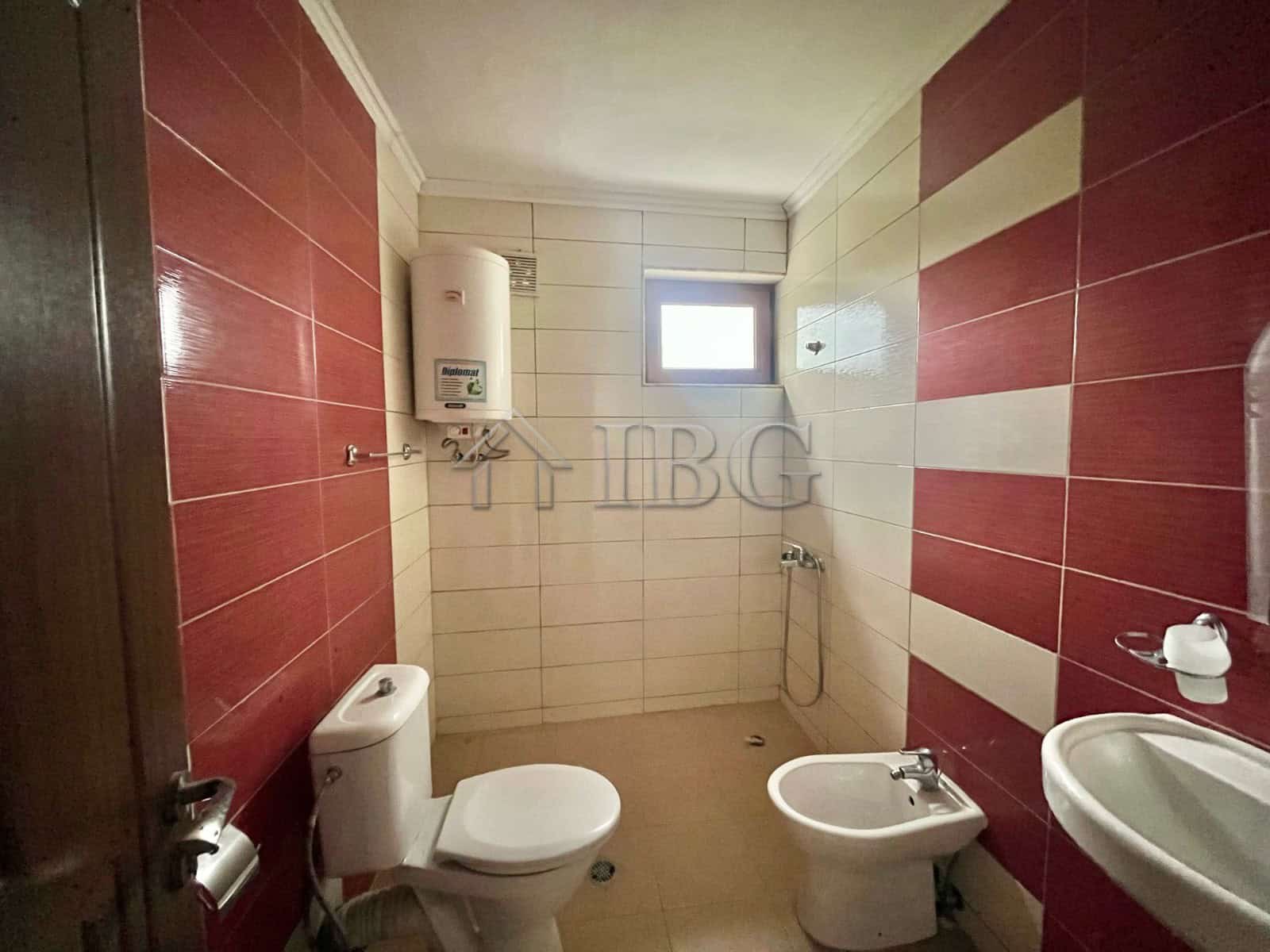 Cozy bathroom with modern fixtures, white and red tiled walls, and a small window for natural light.