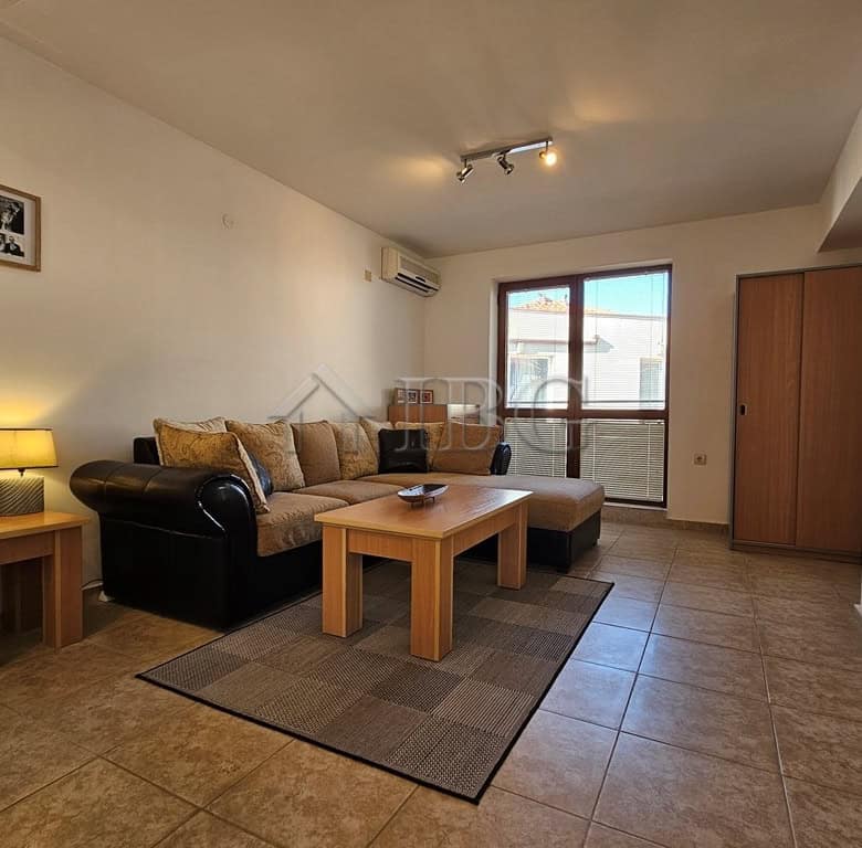 Bright living room with sofa, coffee table, and large window in Sveti Vlas apartment.