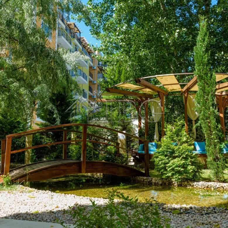 Beautiful garden scene featuring a wooden bridge, lush greenery, and a shaded seating area in Sunny.
