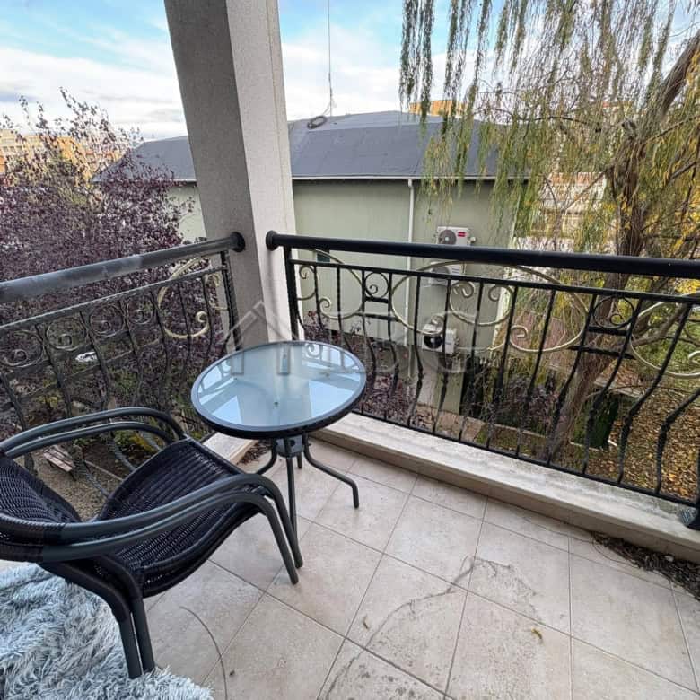 Balcony with outdoor seating overlooking the pool and surrounding trees at Harmony Palace, Sunny Bea.