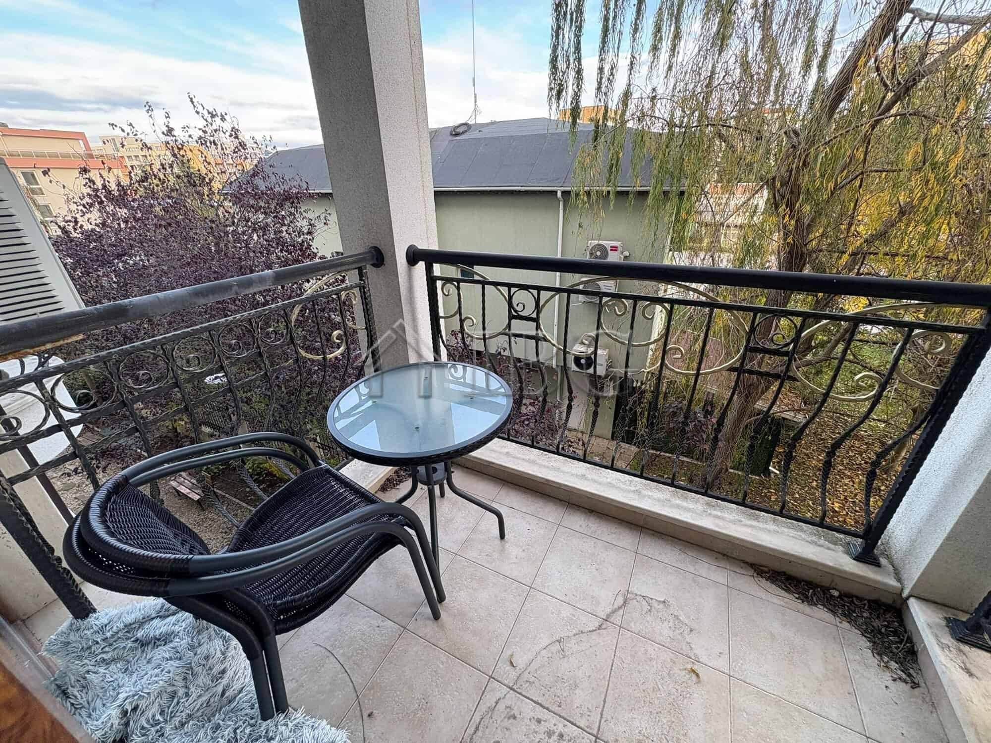 Balcony with outdoor seating overlooking the pool and surrounding trees at Harmony Palace, Sunny Bea.