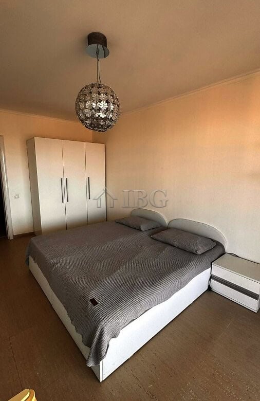 Bedroom with a double bed, wardrobe, and elegant lighting fixture in a seaside apartment.