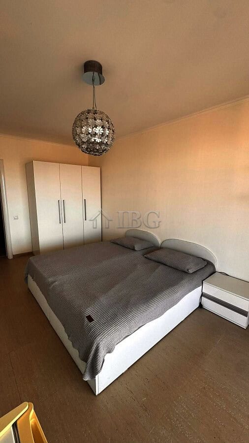 Bedroom with a double bed, wardrobe, and elegant lighting fixture in a seaside apartment.
