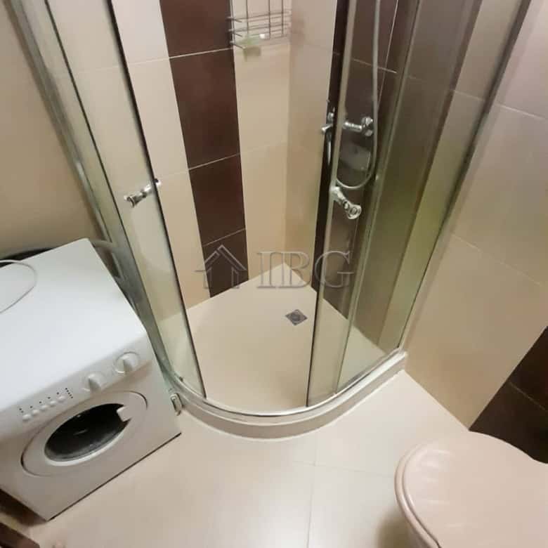 Small bathroom shower stall with modern fixtures and tiled walls in a resort setting.