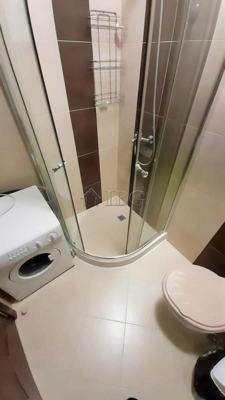 Small bathroom shower stall with modern fixtures and tiled walls in a resort setting.