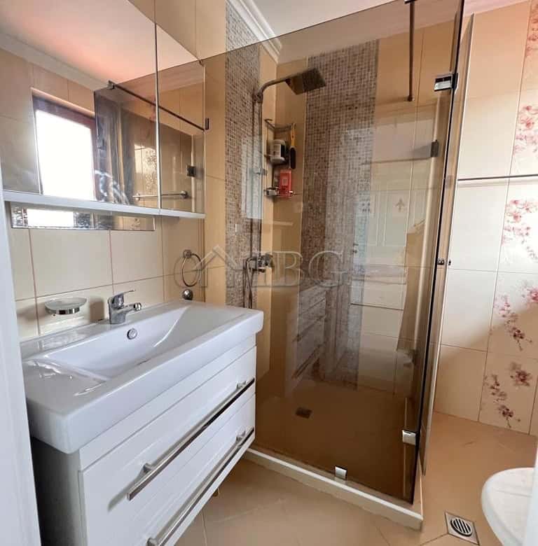Bright bathroom with glass shower enclosure and modern fixtures.