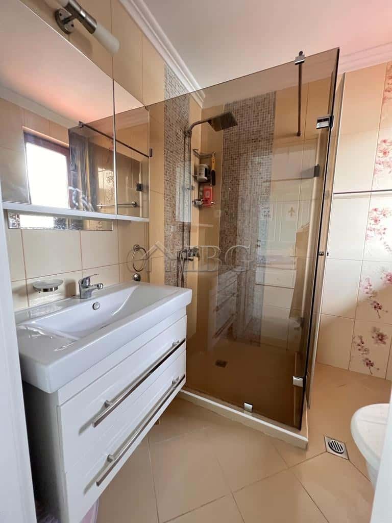Bright bathroom with glass shower enclosure and modern fixtures.