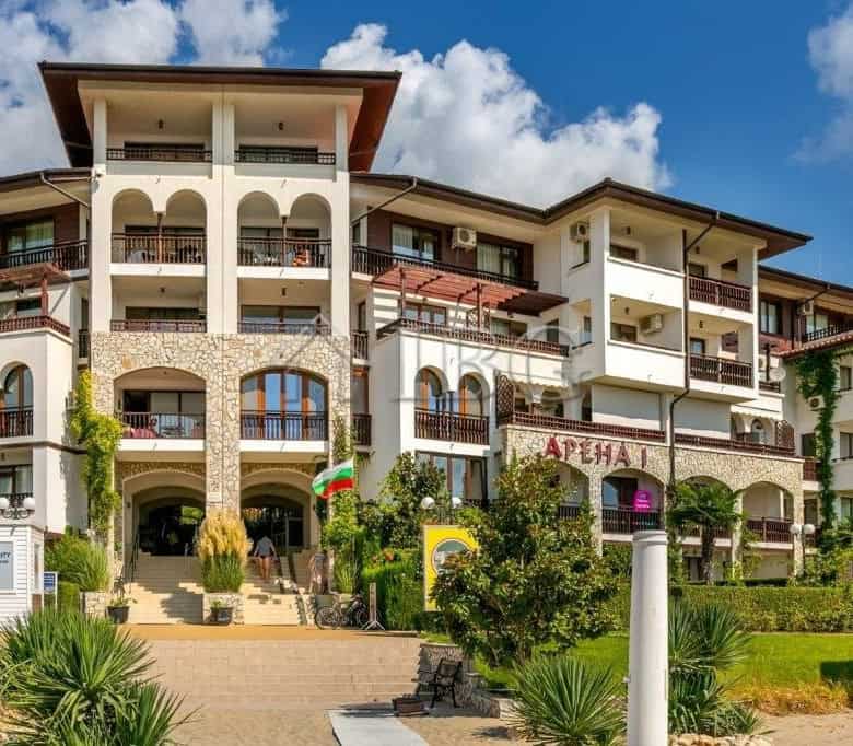 Seaside apartment complex with balconies, greenery, and clear blue sky in Sveti Vlas.