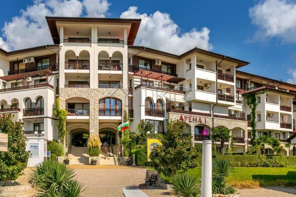 Seaside apartment complex with balconies, greenery, and clear blue sky in Sveti Vlas.