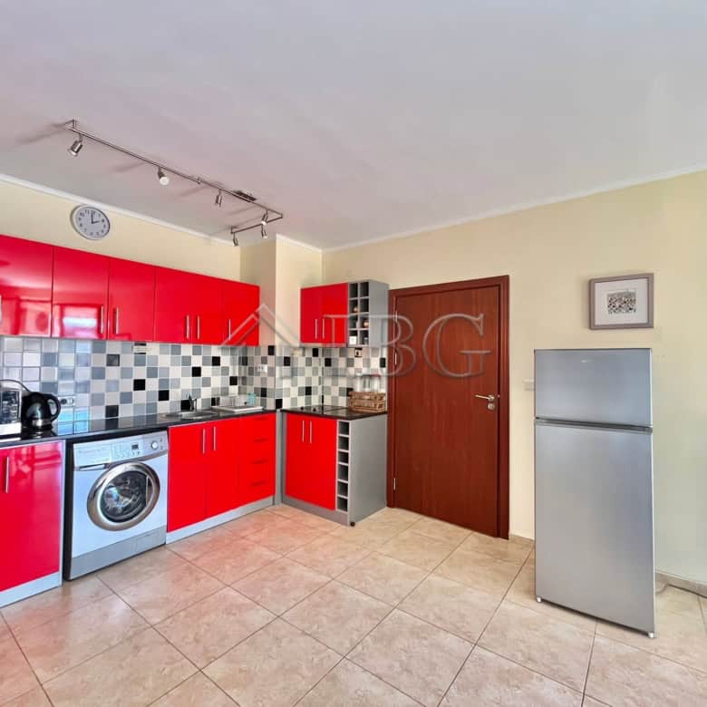 Bright, modern kitchen with red cabinets and essential appliances in Ravda.