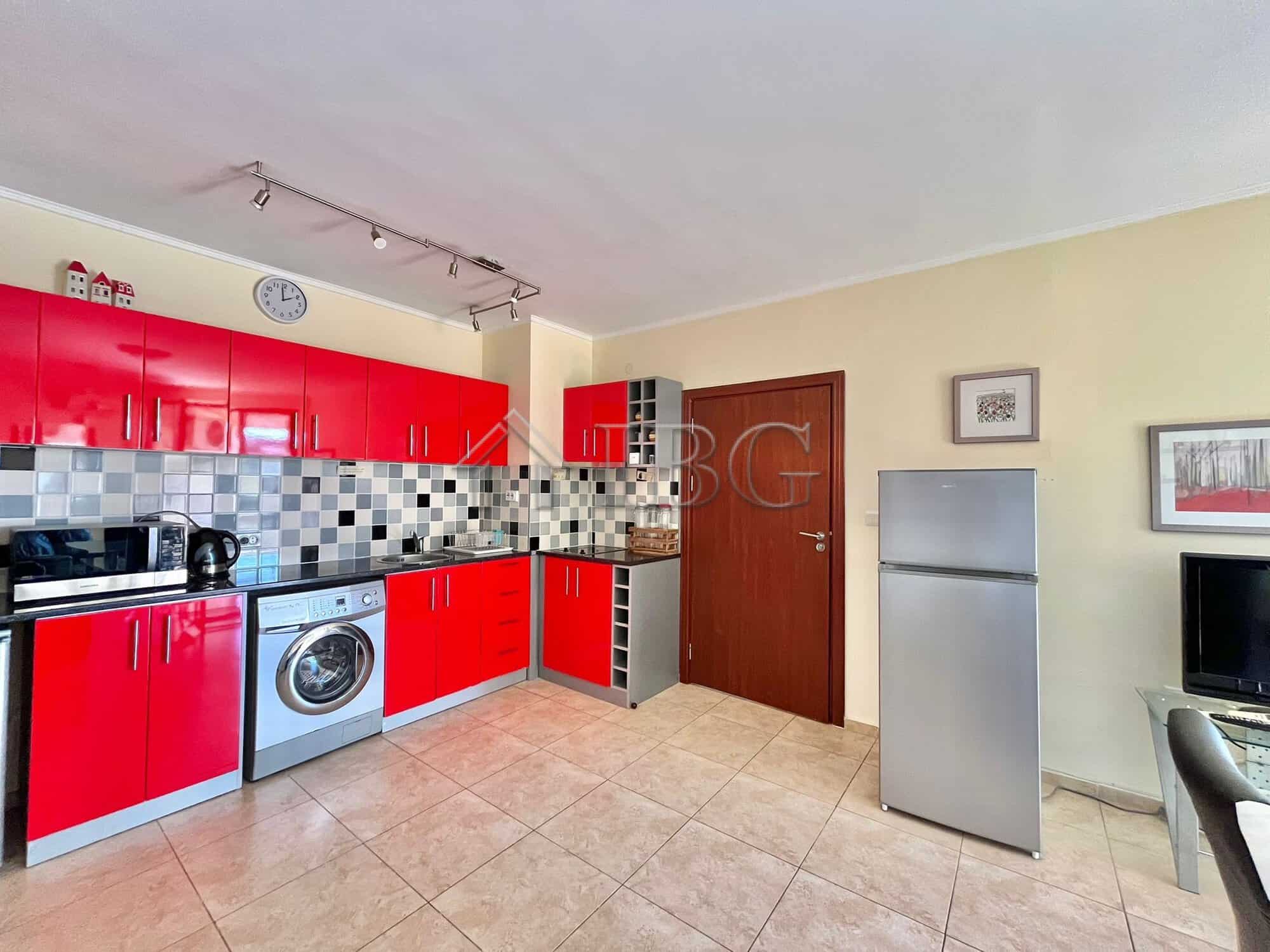 Bright, modern kitchen with red cabinets and essential appliances in Ravda.