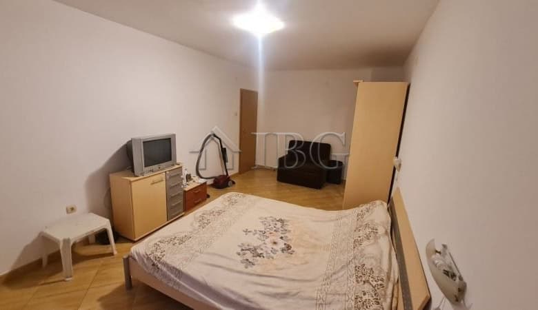 Bedroom with bed, TV, and minimal furniture in a sunny apartment.