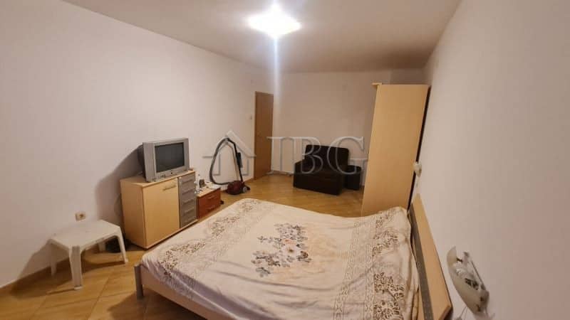 Bedroom with bed, TV, and minimal furniture in a sunny apartment.