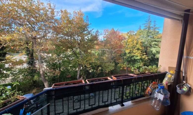 Balcony of a 2-bedroom apartment overlooking lush trees and a clear blue sky, perfect for relaxing a.