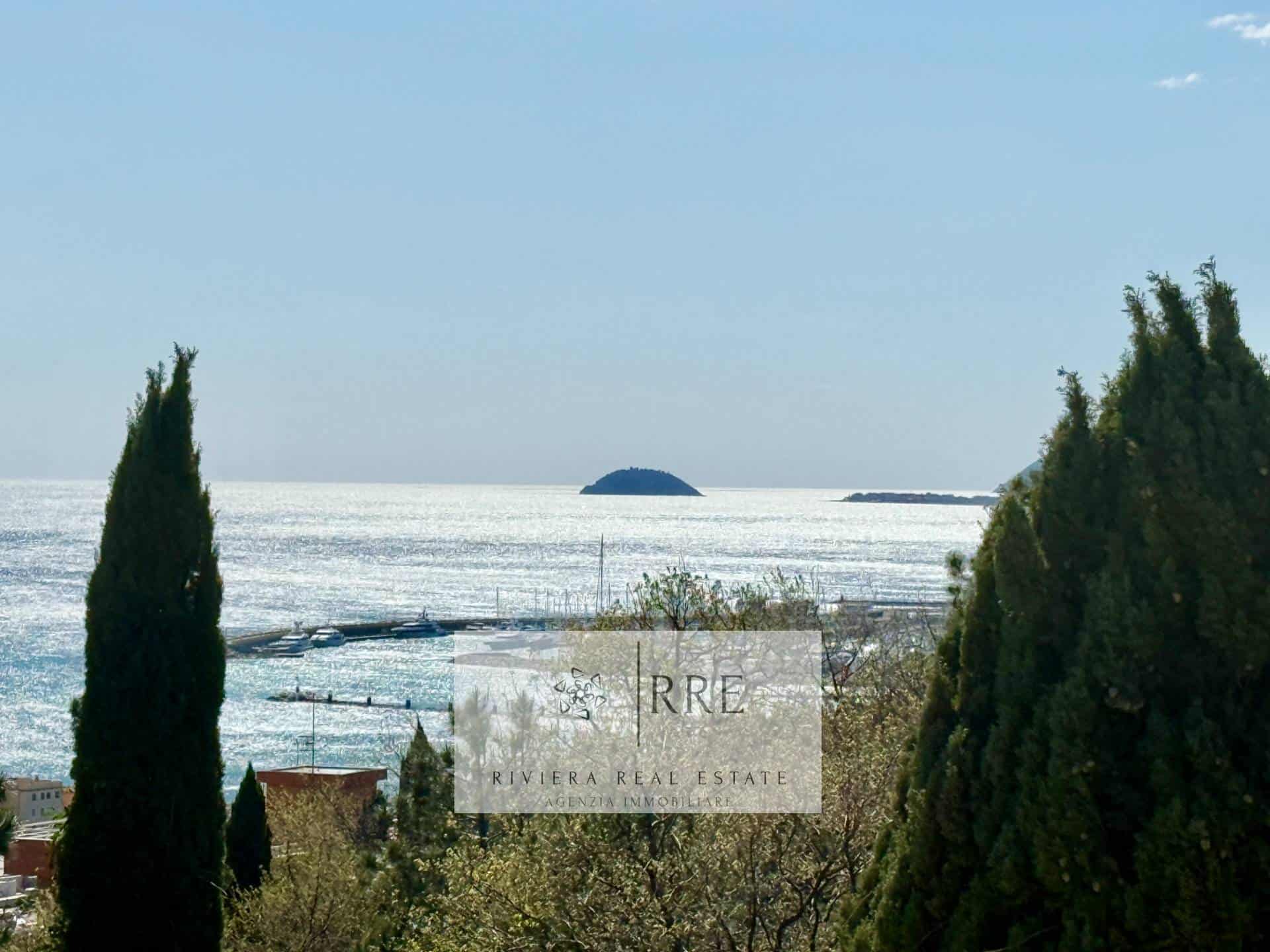 Scenic coastal landscape featuring tall trees, calm ocean, and distant islands.