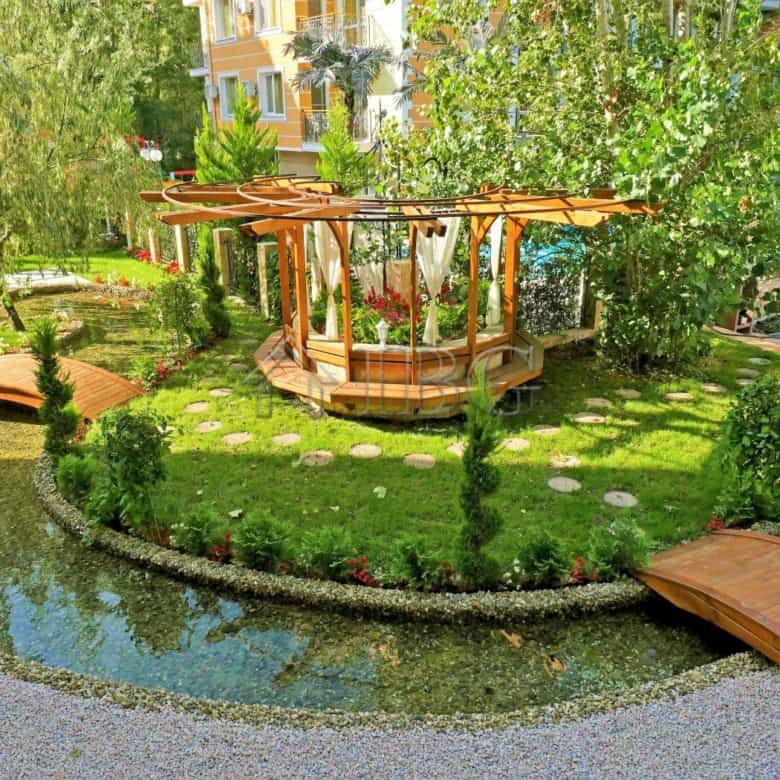 Garden with wooden walkways and a small pond in a residential complex at Sunny Beach.