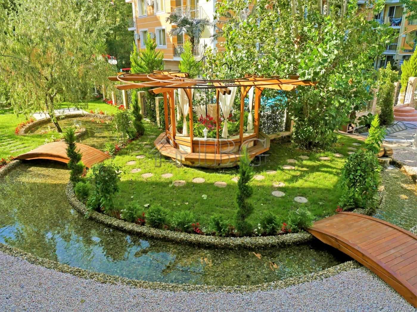 Garden with wooden walkways and a small pond in a residential complex at Sunny Beach.