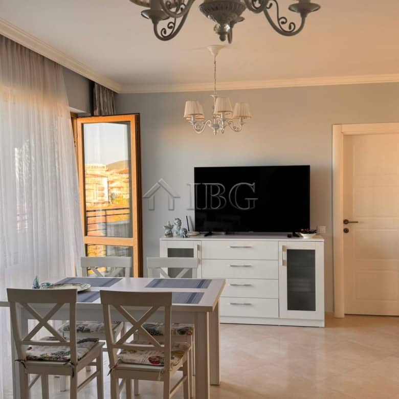 Bright living room with dining table, chandelier, and balcony view in Sveti Vlas apartment.