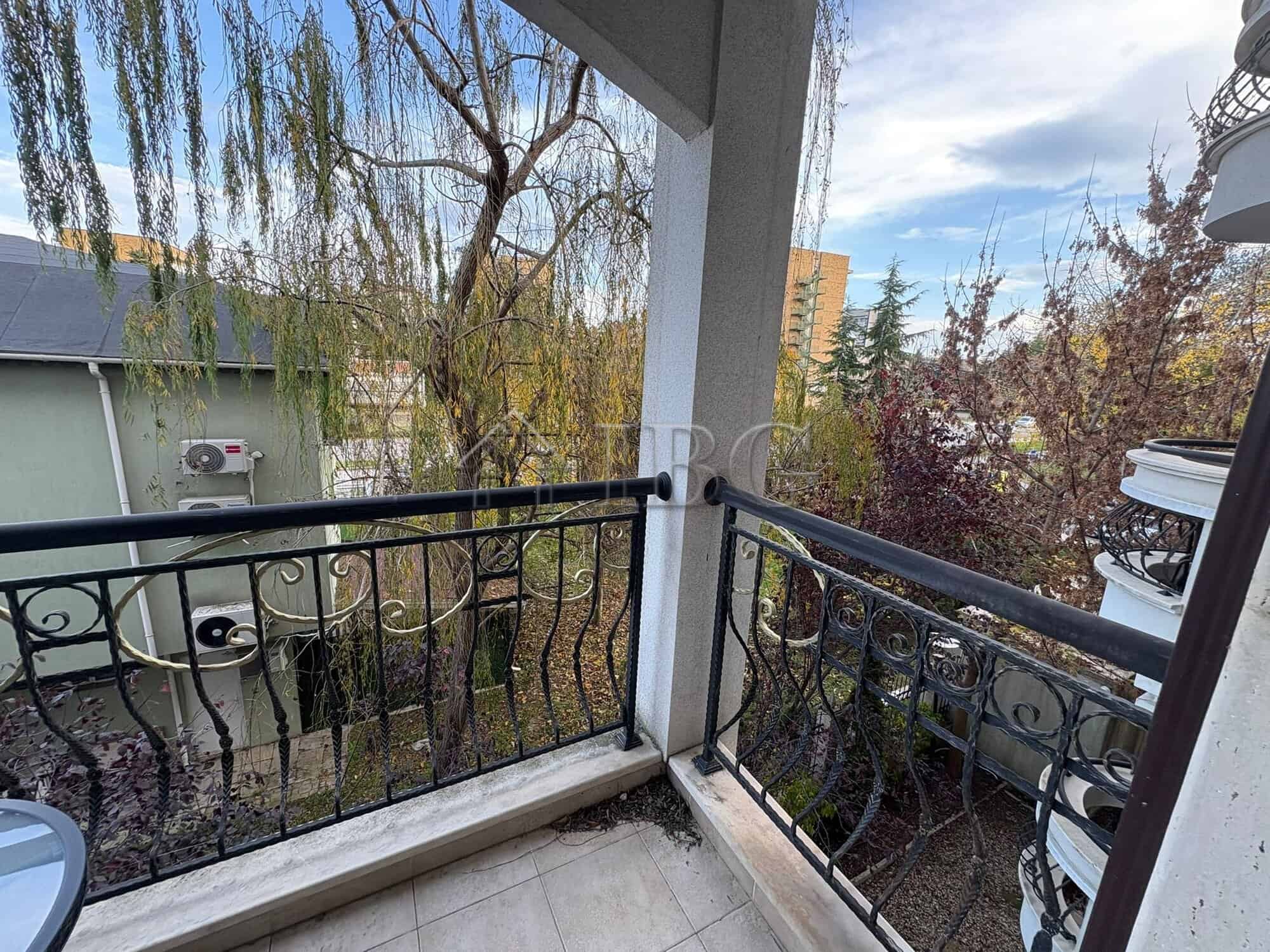 Balcony with pool view overlooking trees and neighboring buildings in Harmony Palace, Sunny Beach.