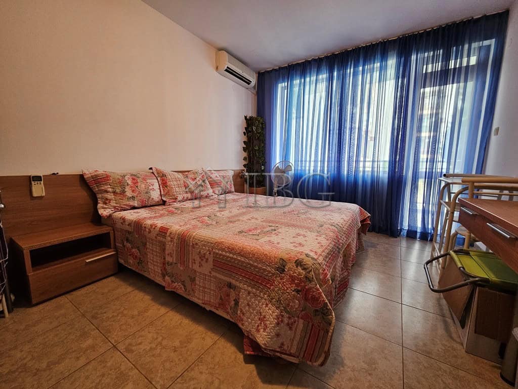 Bright bedroom with large window and blue curtains in Sveti Vlas apartment.