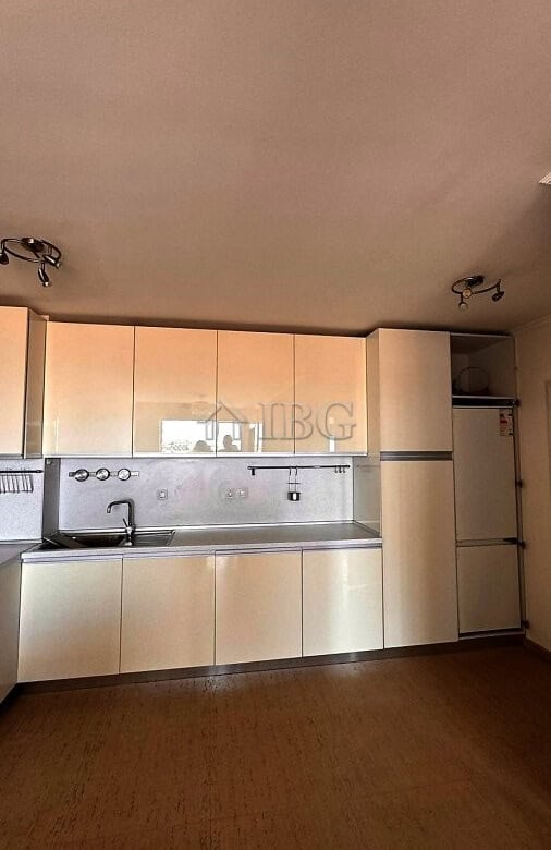 Kitchen with beige cabinets, stainless steel sink, and minimalistic design.